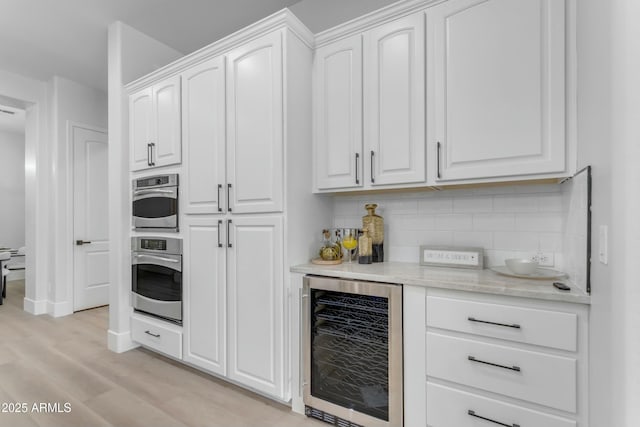 kitchen featuring white cabinets, beverage cooler, and stainless steel oven