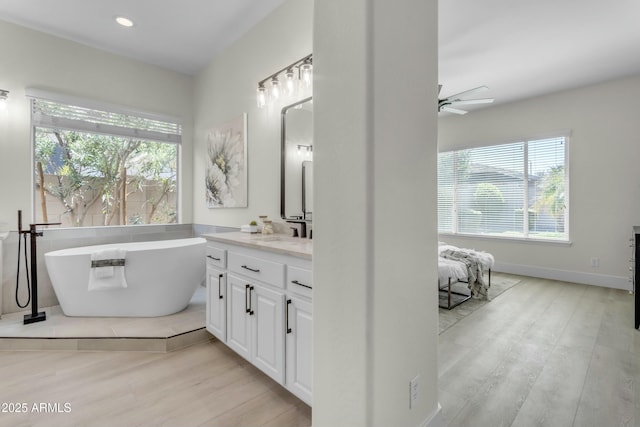 bathroom featuring vanity, a tub to relax in, plenty of natural light, and ceiling fan