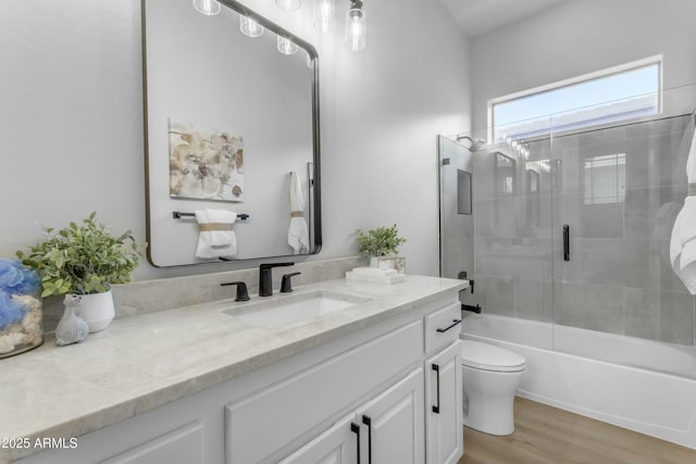 full bathroom with bath / shower combo with glass door, vanity, wood-type flooring, and toilet