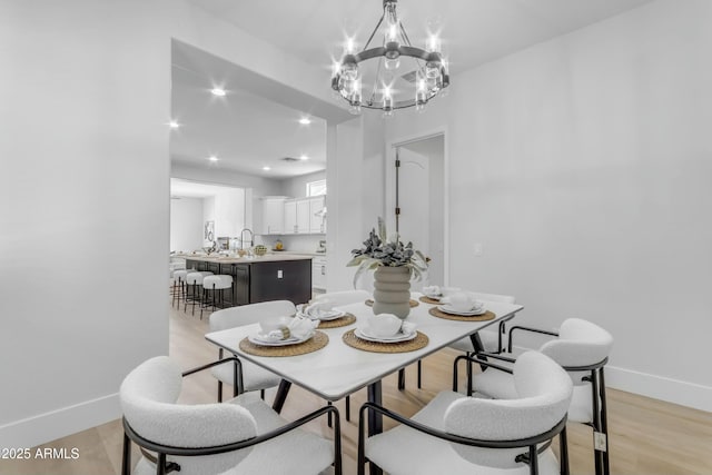 dining area with light hardwood / wood-style floors and an inviting chandelier