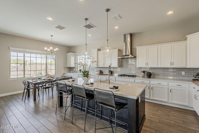 3310 E Los Gatos Dr, Phoenix, AZ 85050 - kitchen featuring wall chimney exhaust hood, stainless steel gas cooktop, a chandelier, decorative backsplash, and a kitchen bar