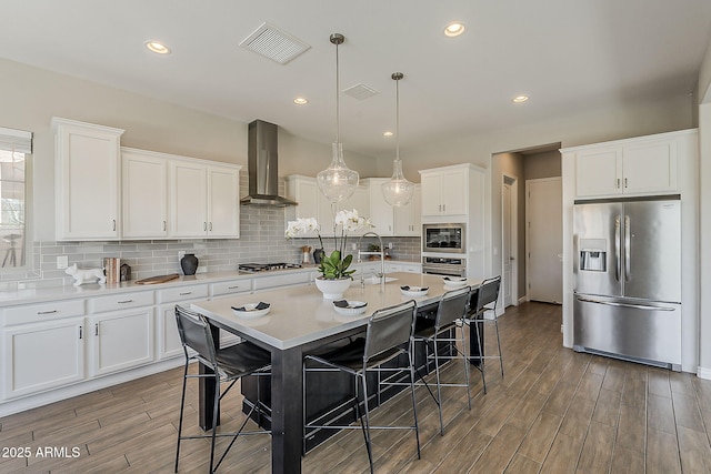 3310 E Los Gatos Dr, Phoenix, AZ 85050 - kitchen featuring stainless steel appliances, wall chimney exhaust hood, a breakfast bar, white cabinetry, and recessed lighting