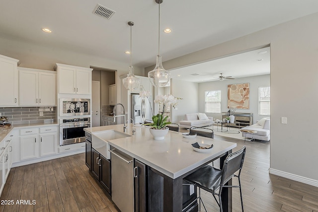 3310 E Los Gatos Dr, Phoenix, AZ 85050 - kitchen with stainless steel appliances, a sink, light countertops, dark wood-type flooring, and backsplash