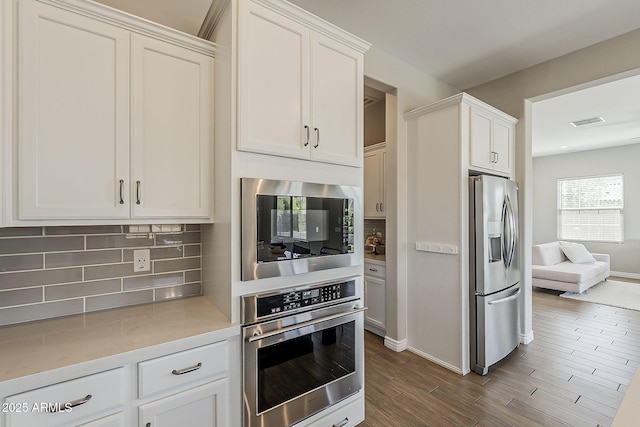 3310 E Los Gatos Dr, Phoenix, AZ 85050 - kitchen featuring appliances with stainless steel finishes, decorative backsplash, white cabinets, and dark wood-type flooring