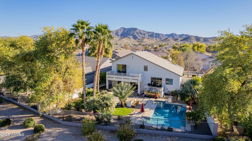 rear view of house featuring a fenced in pool, a patio area, a mountain view, and a balcony