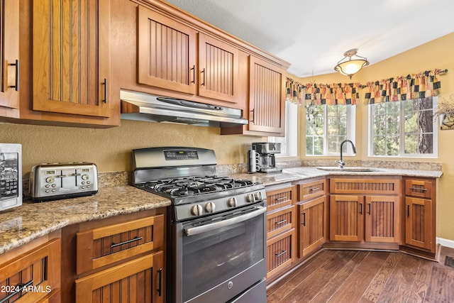 kitchen featuring dark wood-type flooring, light stone counters, sink, and stainless steel gas range oven