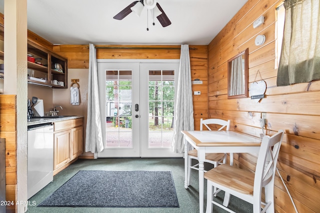 dining space featuring ceiling fan, wood walls, light carpet, and french doors