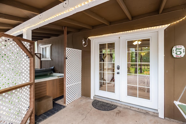 view of exterior entry featuring french doors, a hot tub, and a patio