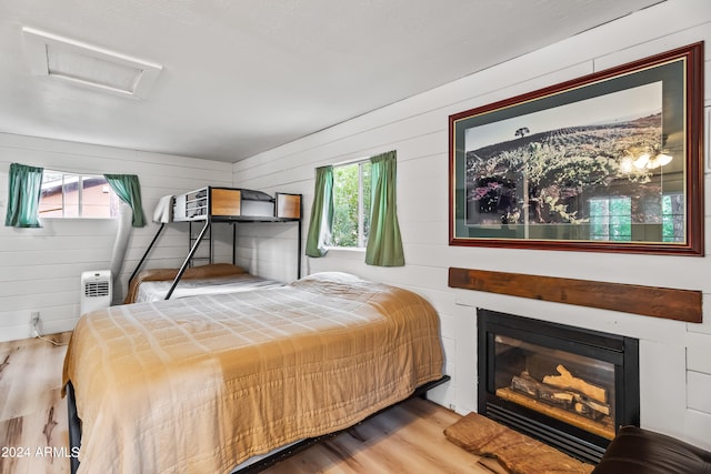 bedroom with wooden walls and light hardwood / wood-style floors