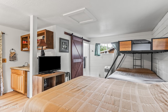 unfurnished bedroom featuring a barn door and light hardwood / wood-style floors