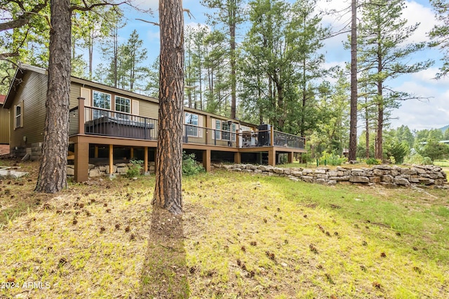 rear view of property featuring a wooden deck and a lawn