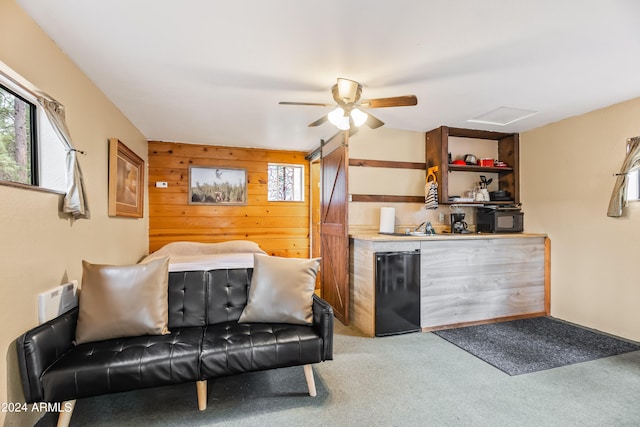 living room featuring carpet, ceiling fan, and a barn door