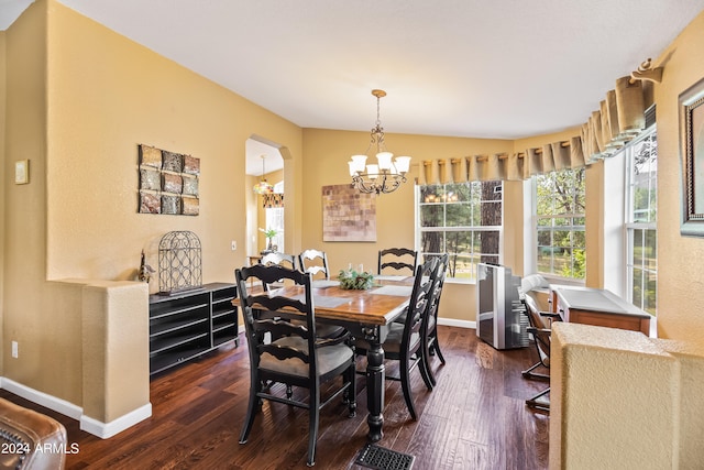 dining space featuring dark wood-type flooring, lofted ceiling, and a notable chandelier