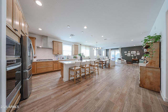 10964 W Garfield St, Avondale, AZ 85323 - kitchen with wall chimney range hood, appliances with stainless steel finishes, open floor plan, light countertops, and light wood-style flooring