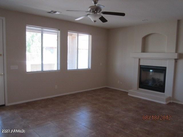 9018 W Superior Ave, Tolleson, AZ 85353 - unfurnished living room featuring a glass covered fireplace, plenty of natural light, and ceiling fan