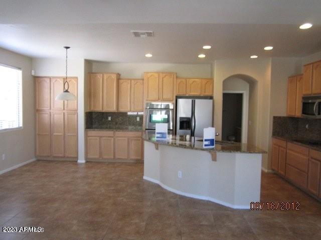 9018 W Superior Ave, Tolleson, AZ 85353 - kitchen featuring stainless steel appliances, backsplash, light brown cabinetry, recessed lighting, and a breakfast bar area