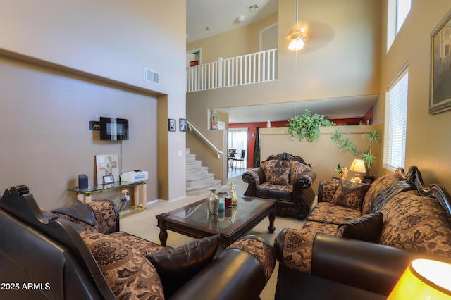 carpeted living room featuring a towering ceiling and ceiling fan