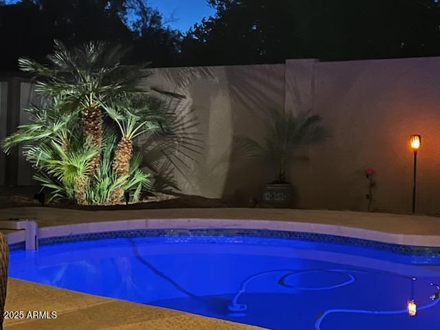 view of pool at twilight