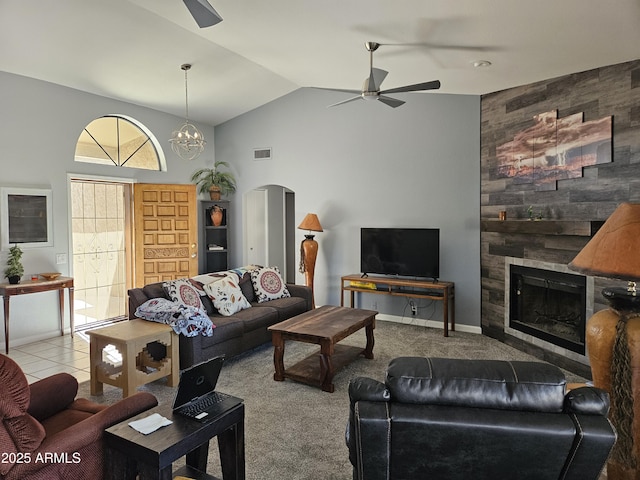 carpeted living room with wood walls, ceiling fan with notable chandelier, lofted ceiling, and a large fireplace