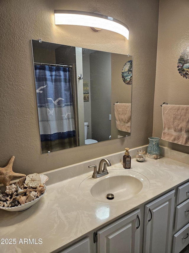 bathroom featuring curtained shower, toilet, and vanity