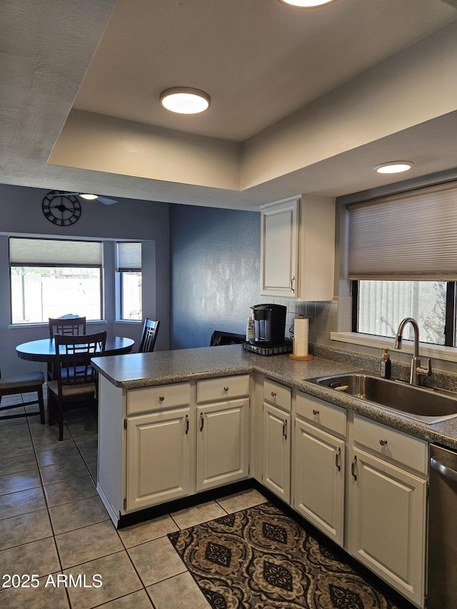 kitchen featuring sink, a raised ceiling, kitchen peninsula, and stainless steel dishwasher