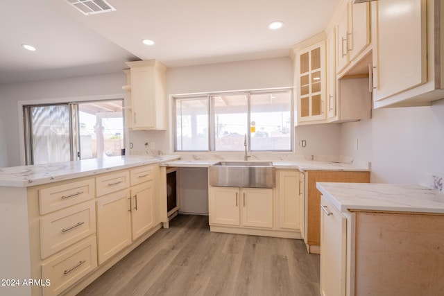 kitchen with cream cabinets, light hardwood / wood-style flooring, and sink