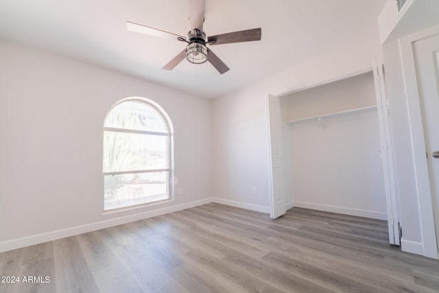 unfurnished bedroom with light hardwood / wood-style floors, ceiling fan, and a closet