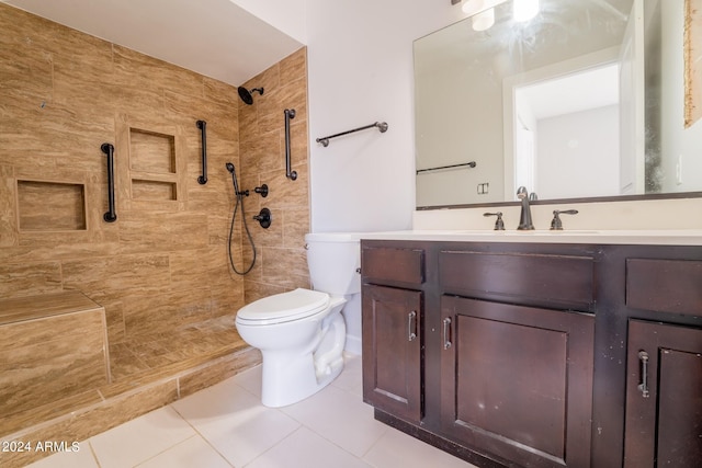 bathroom with a tile shower, tile patterned flooring, vanity, and toilet