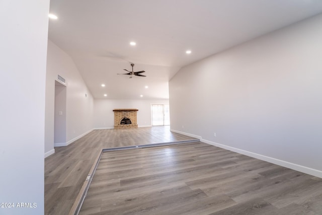 unfurnished living room featuring vaulted ceiling, ceiling fan, hardwood / wood-style flooring, and a fireplace