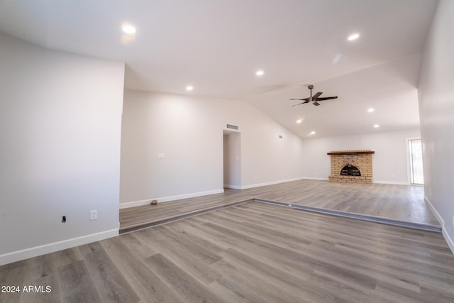 unfurnished living room with lofted ceiling, ceiling fan, hardwood / wood-style flooring, and a fireplace