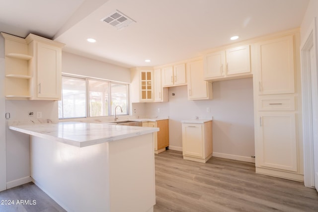 kitchen with light hardwood / wood-style floors, sink, and kitchen peninsula