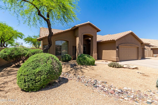 mediterranean / spanish home with an attached garage, a tile roof, and stucco siding