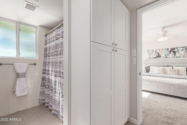 bathroom with tile patterned flooring, ceiling fan, curtained shower, and a textured ceiling