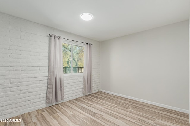 unfurnished room featuring brick wall and light wood-type flooring