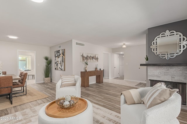 living room featuring a tile fireplace and light wood-type flooring