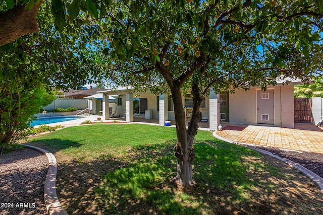 rear view of house featuring a fenced in pool, a patio, and a lawn