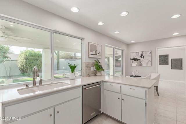 kitchen featuring tasteful backsplash, sink, white cabinets, stainless steel dishwasher, and kitchen peninsula