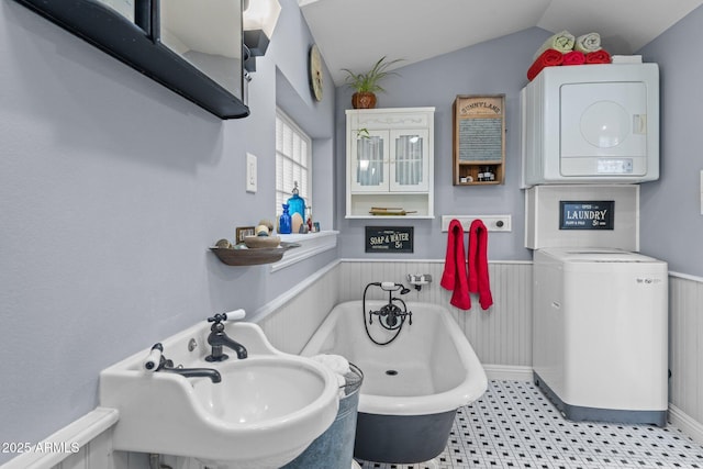 bathroom with a tub to relax in, lofted ceiling, and sink