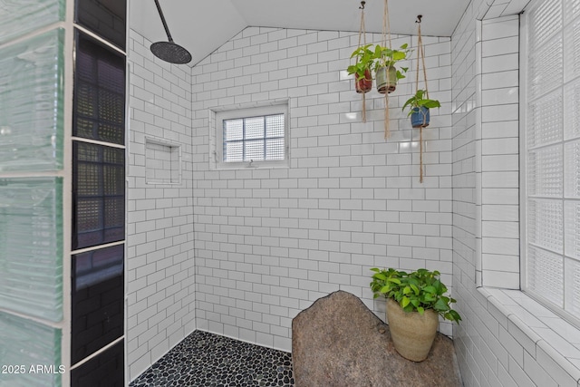 bathroom with a tile shower, tile walls, and lofted ceiling