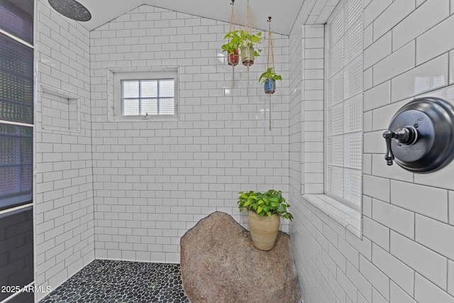 bathroom with a tile shower and vaulted ceiling