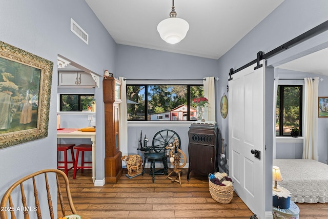 interior space featuring a barn door, wood-type flooring, and lofted ceiling