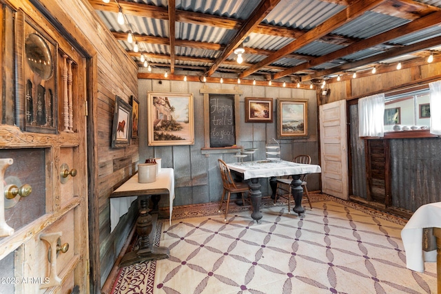 dining area with wood walls, beamed ceiling, and track lighting