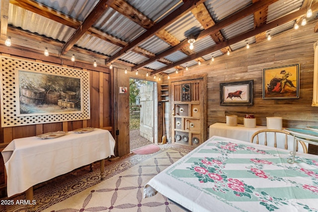 bedroom with lofted ceiling with beams, rail lighting, and wooden walls