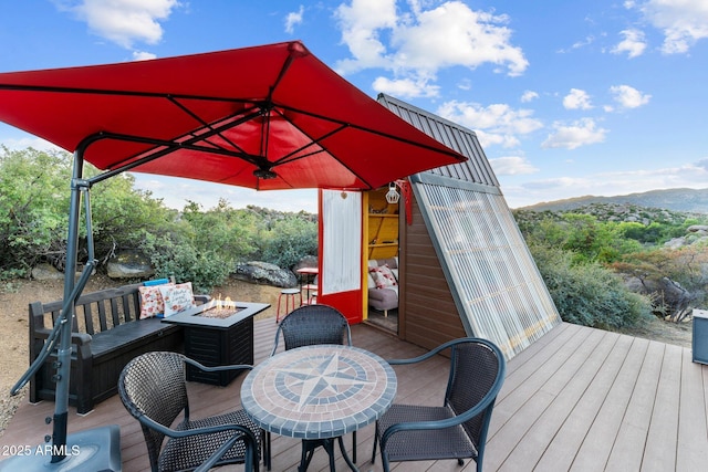 wooden deck featuring a mountain view and an outdoor fire pit