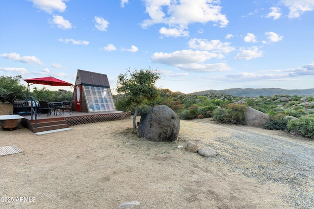 view of yard featuring a deck with mountain view and an outdoor structure