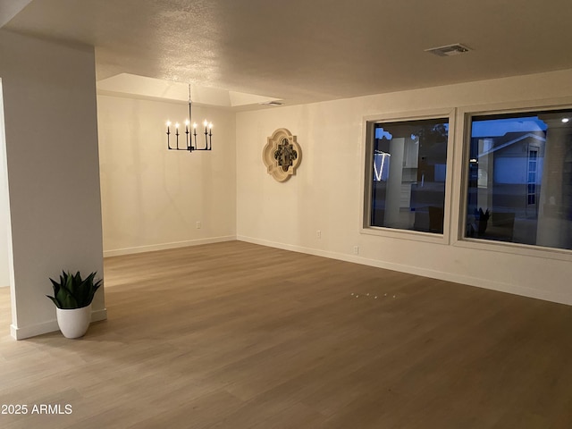 spare room featuring hardwood / wood-style floors, a notable chandelier, and a textured ceiling