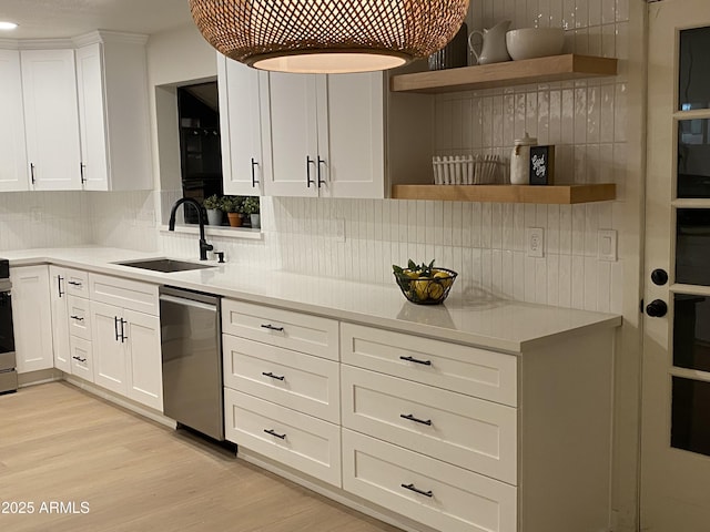 kitchen featuring sink, backsplash, appliances with stainless steel finishes, white cabinets, and light wood-type flooring