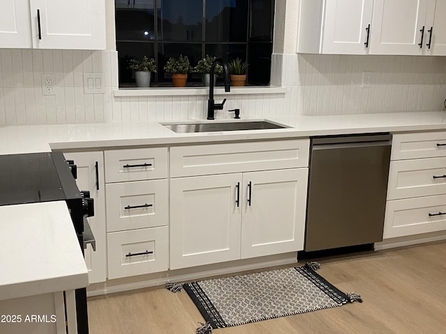 kitchen featuring dishwasher, sink, light wood-type flooring, tasteful backsplash, and white cabinetry