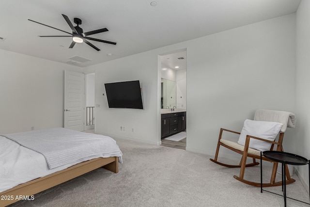 carpeted bedroom with ensuite bath and ceiling fan