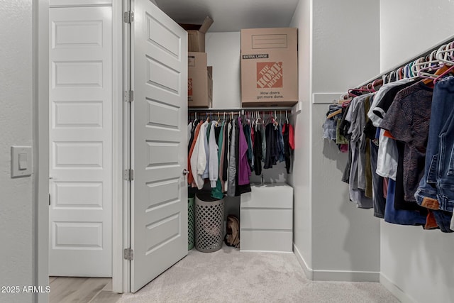 walk in closet featuring light colored carpet